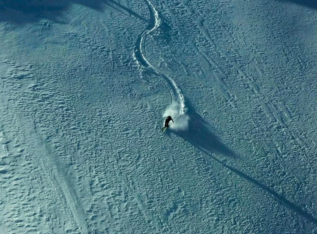 Birds eye view of a solo skier carving off-piste turns on a cat skiing trip in Georgia