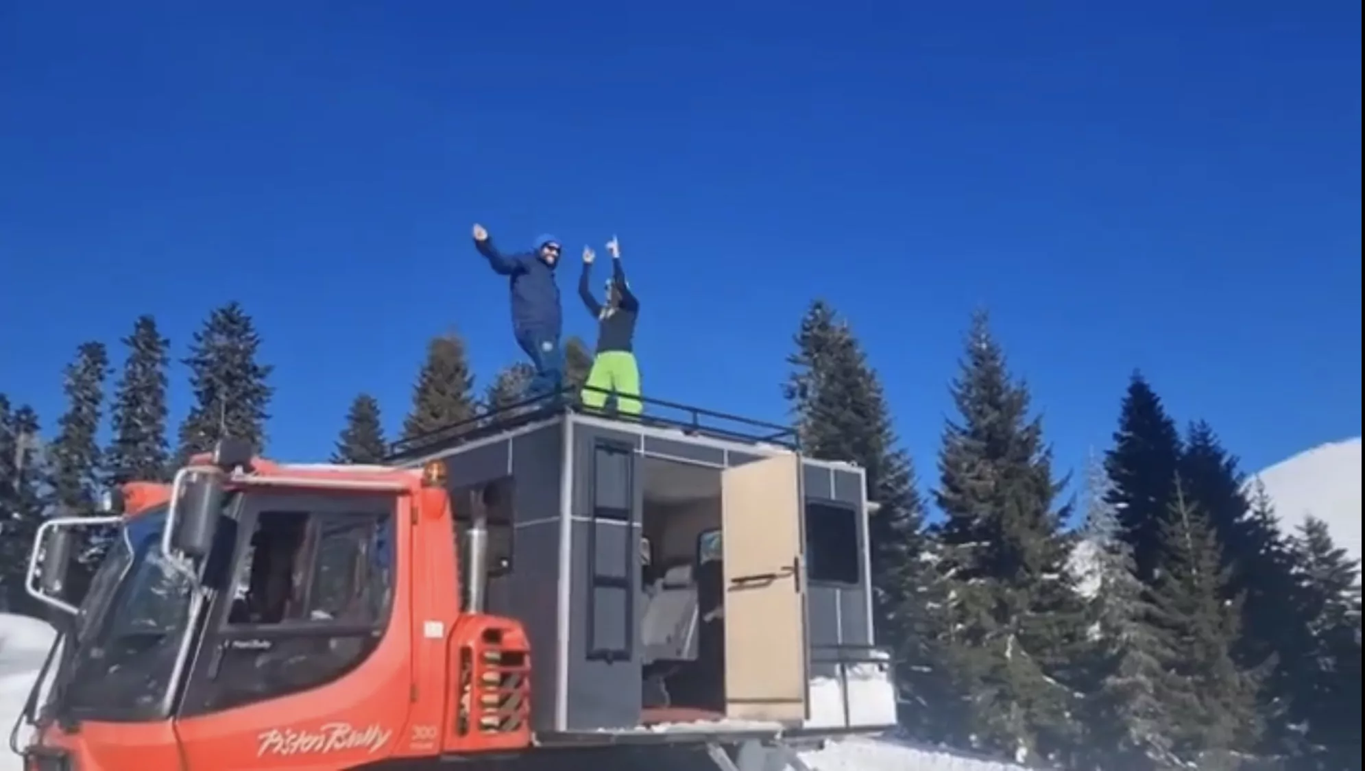 A man and woman dance on top of a snowcat after a day cat skiing in Bakhmaro