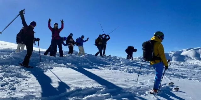 Group of cat skiers and snowboarders at the top of a backcountry run in Georgia's lesser Caucasus mountains