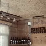 Lounge decoration in Terrace Bakhmaro honesty bar - bottles of Georgian wine light fittings on wood panel walls